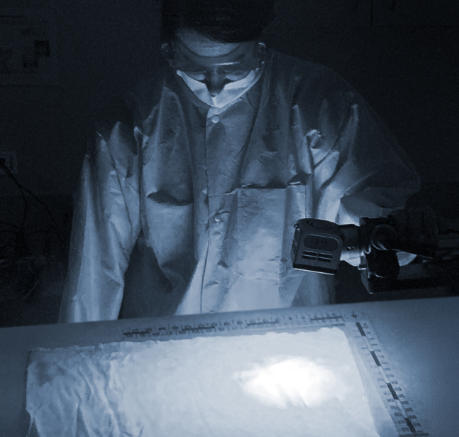 Photo of a lab technician examining a fabric sample with an alternate light source
